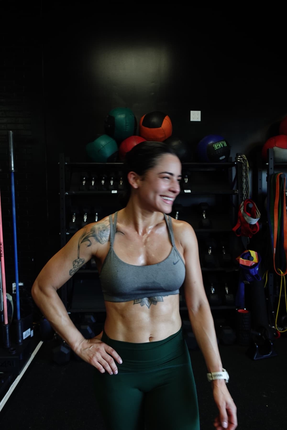 Cynthia Ventura in the gym, smiling between sets — hand on hip, at ease.